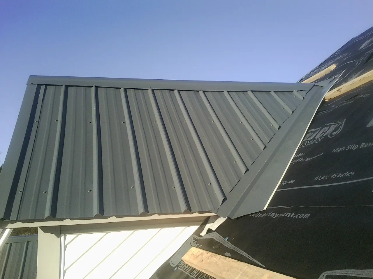 Gray metal roof panels going on over a garage gable in Gauley Bridge