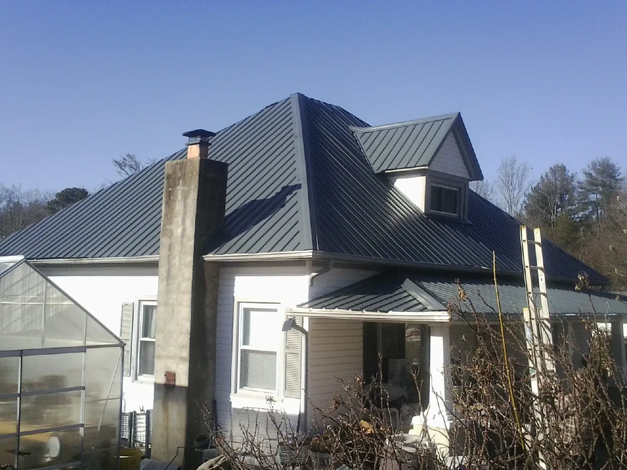 Dark blue standing seam metal roof on a white farmhouse with dormer — Slate & Tile Roof Repair by Roofing Brothers in Gauley Bridge