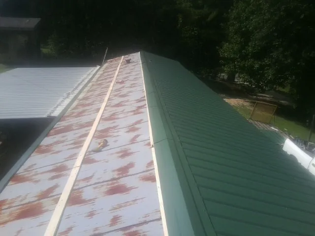 Old rusted panels beside newly installed green metal roofing — Wind Damage Roof Repair by Roofing Brothers in Gauley Bridge