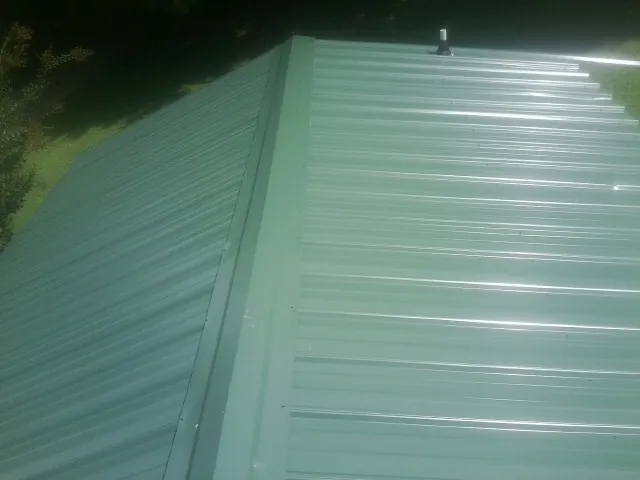 New green metal panels meeting at the ridge of a roof — Flat Roof Repair work by our crew in Gauley Bridge