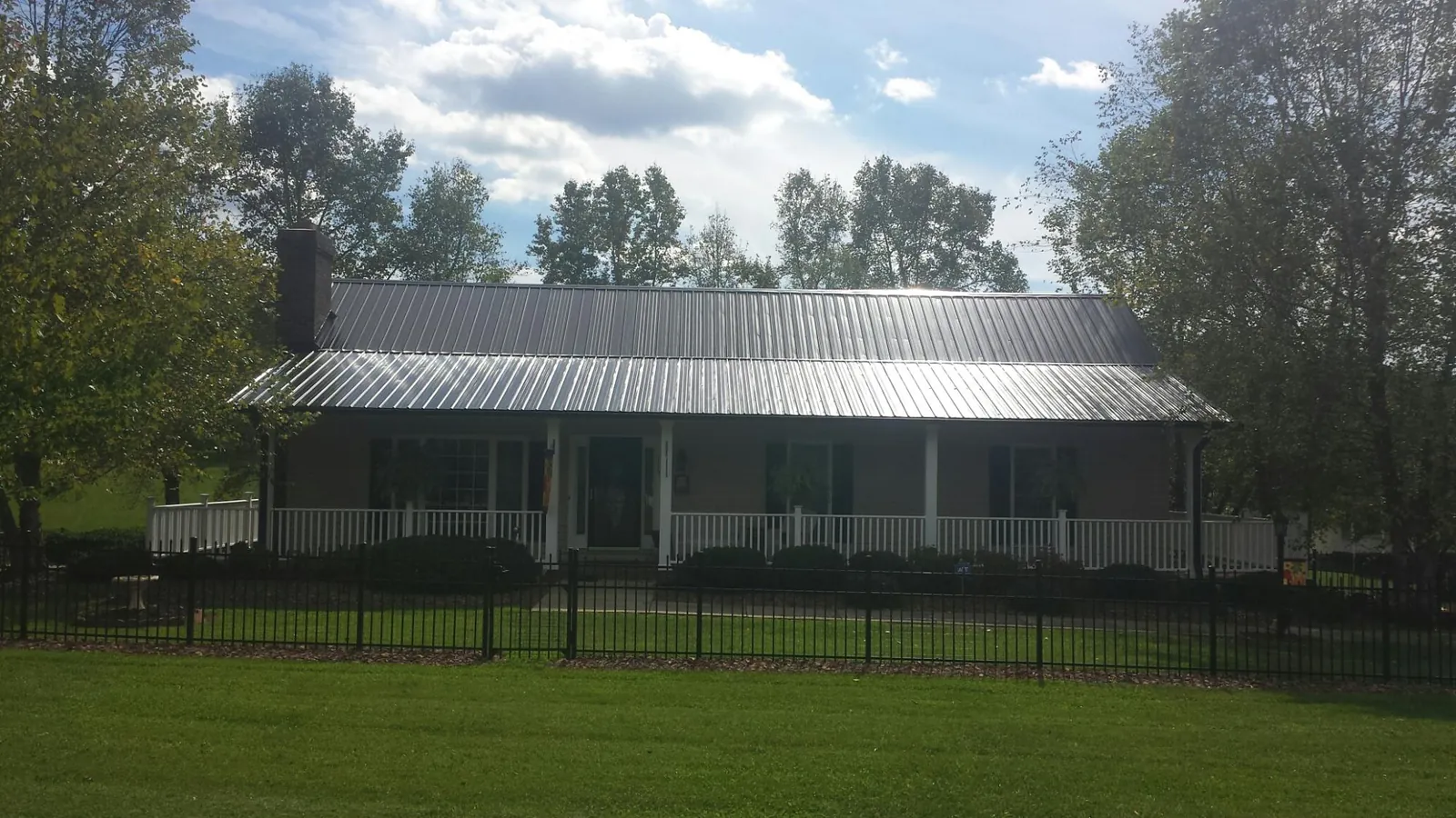 Gray metal roof on a brick ranch with a full width front porch — Gutter Guard Installation work by our crew in Gauley Bridge