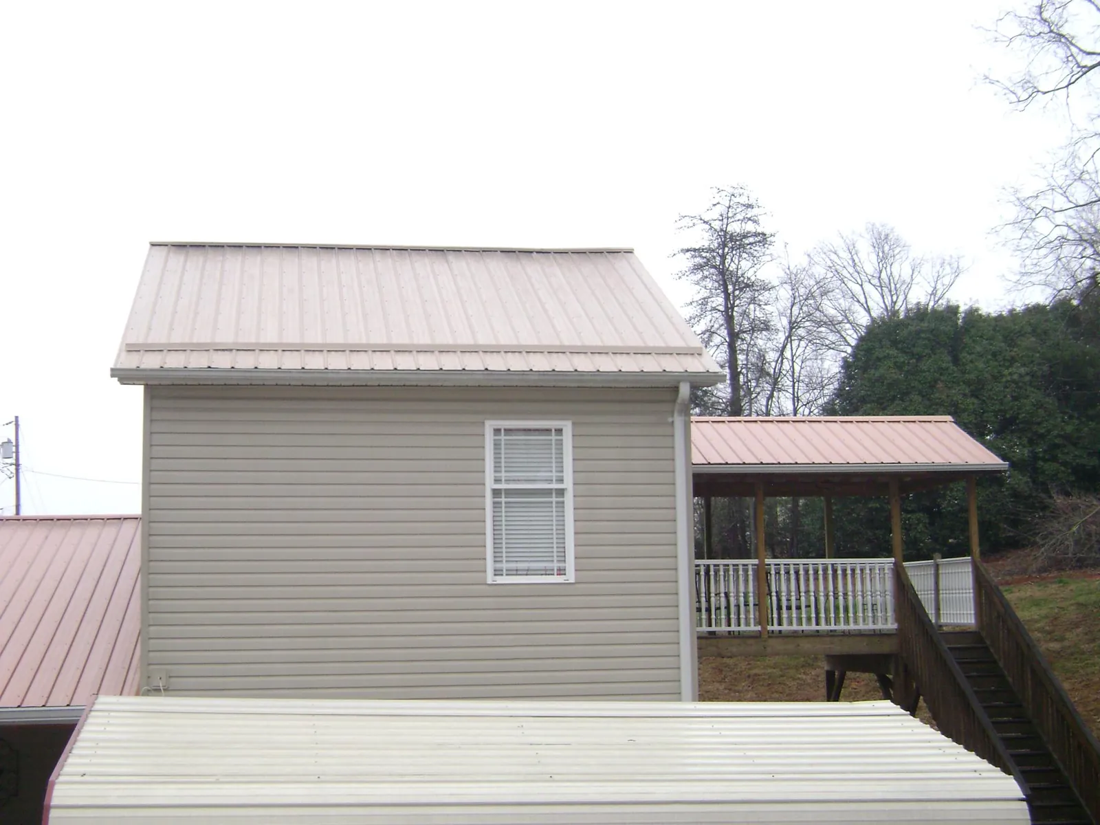 Tan metal roofs on a two story addition and attached porch, from a Roof Replacement job in Gauley Bridge