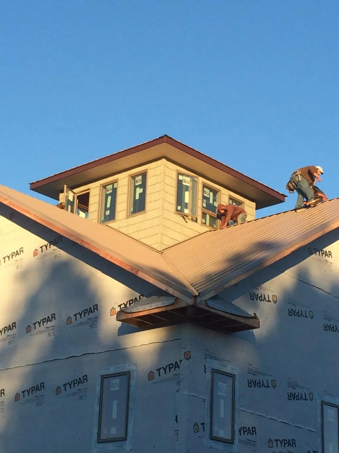 Roofers working around a rooftop cupola on a new metal roof at sunset — Roof Waterproofing in Gauley Bridge by Roofing Brothers